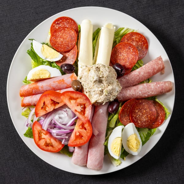 Antipasto salad with pepperoni, salami, ham, cheese, tuna, olives, tomatoes, onions, and hard-boiled eggs.