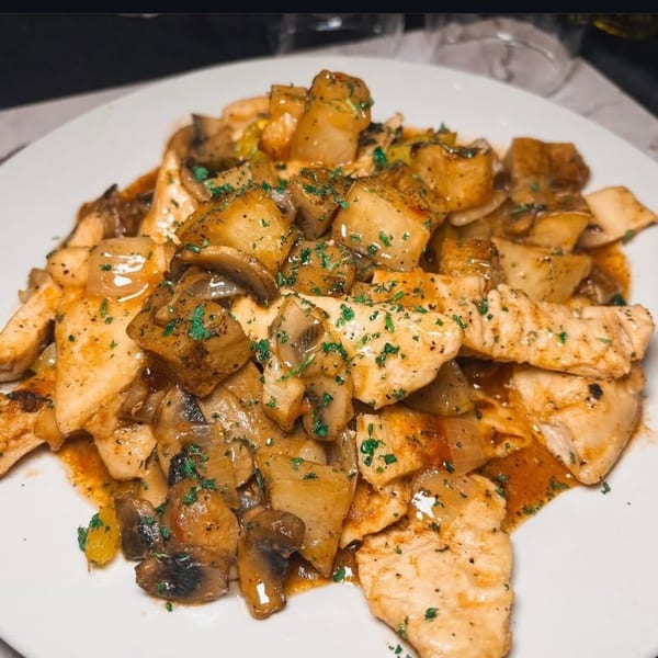 Chicken and mushrooms in a savory sauce, garnished with parsley, served on a white plate.
