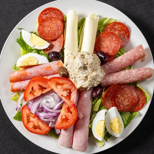 Antipasto salad with pepperoni, ham, salami, provolone, tuna, tomatoes, onions, olives, and hard-boiled eggs.