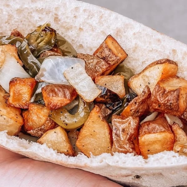 Close-up of a pita bread filled with roasted potatoes, onions, and green peppers.