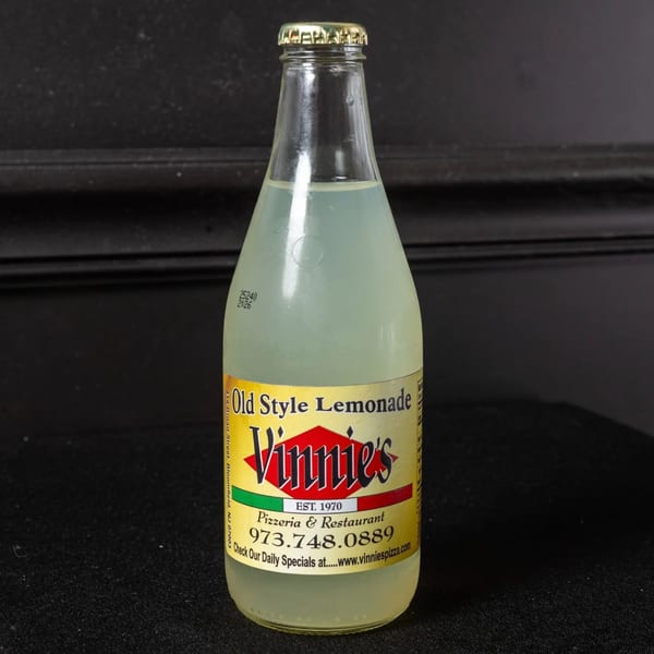A glass bottle of Vinnie's Old Style Lemonade with a yellow label on a dark background.