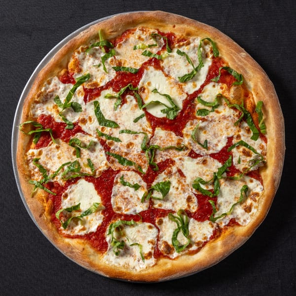 Vinnie's Pizzeria's Margherita pizza with fresh mozzarella, tomato sauce, and basil on a dark surface.
